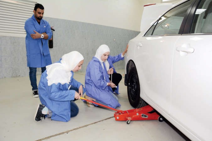 طالبتان تقومان بفك وتركيب اطار السيارة﻿