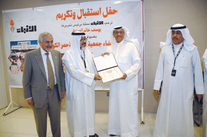 انور الحساوي يتسلم التكريم من الزميل يوسف عبدالرحمن هاني الشمري