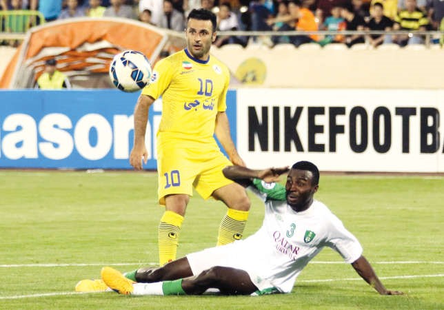 مدافع الاهلي السعودي اسامة هوساوي يبعد الكرة قبل وصول مهاجم نفط طهران غلام رضا رضائي افپ﻿