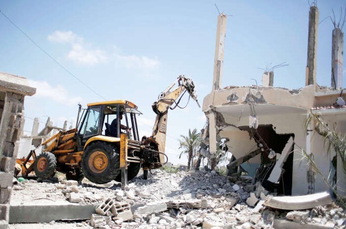 بلدوزر فلسطيني يزيل بقايا منزل دمره الاحتلال الاسرائيلي خلال عدوانه على غزة العام الماضيافپ ﻿