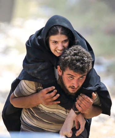 لاجئ سوري يحمل سيدة مريضة على ظهره لدى فرارهما من المعارك بين المقاتلين الاكراد وداعشباتجاه الاراضي التركيةاپ