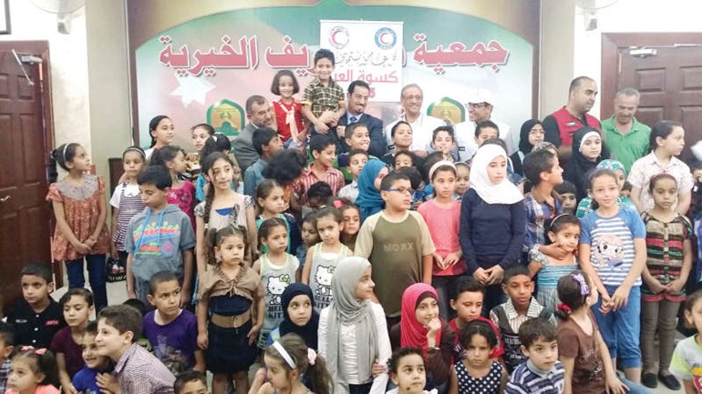 السفير دحمد الدعيج متوسطا الايتام وحفظة القران خلال حفل الافطار الجماعي 