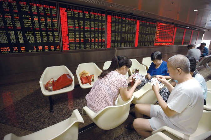 ﻿مستثمرون صينيون يراقبون اسعار الاسهم خلال لعبهم للورقافپ﻿