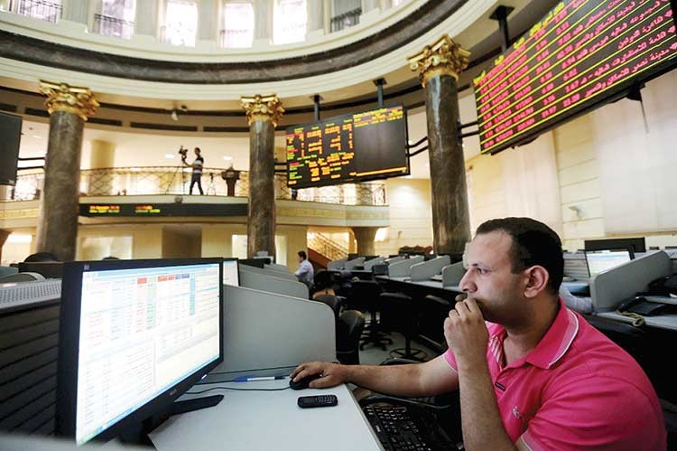 حالة من الذهول تبدو على مستثمر في قاعة التداولات بالبورصة المصرية﻿﻿امس وفي الخلفية تظهر شاشة التداول باللون الاحمر	رويترز﻿