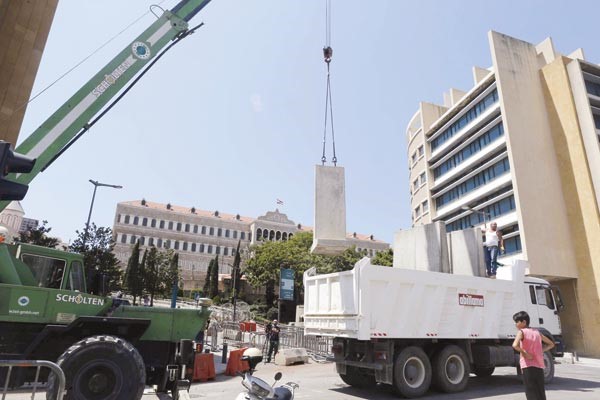 عمال ينزلون حواجز اسمنتية مرتفعة لنصبها حول السراي الحكومي وسط بيروت رويترز