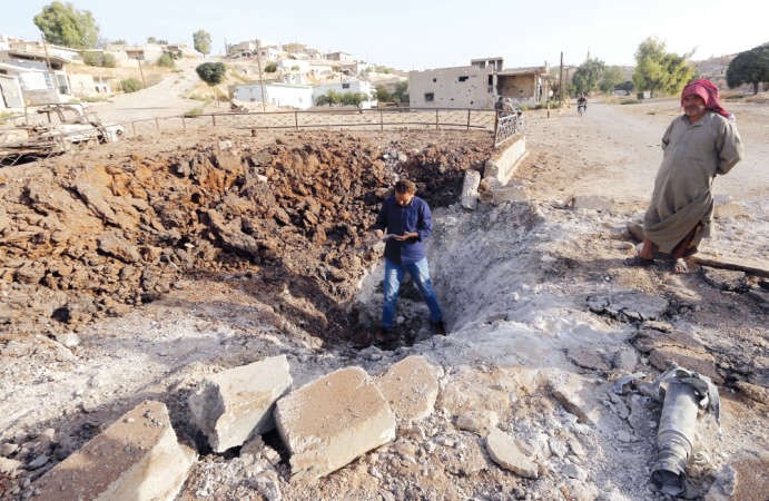 سوريان يعاينان اثار ضربة جوية روسية فيالريف الشمالي لحماة امس رويترز