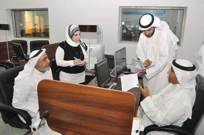 احد الموظفين يشرح للمراجع خالد الفيلكاوي سير عمل معاملته بحضور العازمي والزميلة دارين العلي﻿