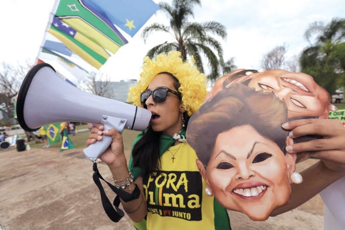 متظاهرة تحمل اقنعة تمثل الرئيسة ديلما روسيف خلال احتجاج امام المحكمة الفيدرالية في برازيليا امس الاول﻿