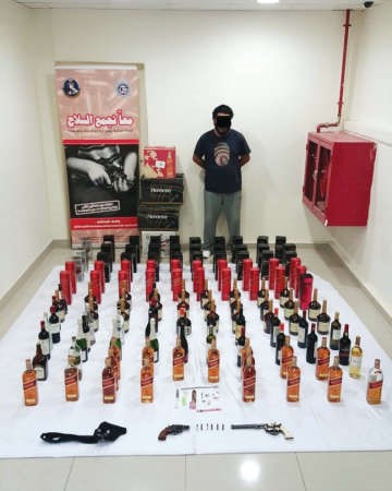 المواطن وامامه المضبوطات من الخمور والاسلحة﻿