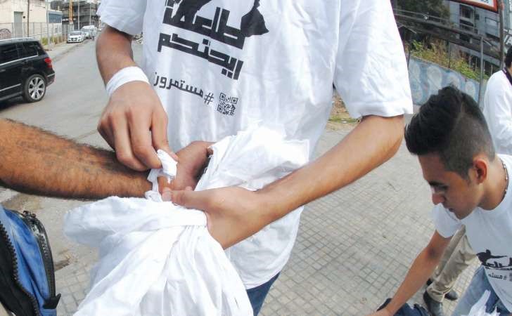 ناشطون من حملة طلعت ريحتكم خلال توزيع شريط ابيض ومنشورات على سائقي السيارات والمارة يدعون فيها الى مسيرة اليوم محمود الطويل 