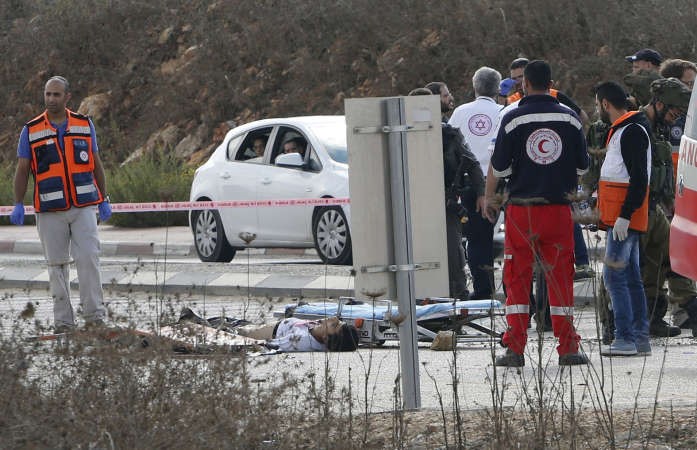 جثة الشهيد الفلسطيني على الارض بعد اطلاق النار عليه برصاص جنود اسرائيليين بالضفة الغربية وفي الاطار جندي ممسك بيد الشاب الفلسطيني الذي طعن اسرائيليا امس رويترز 