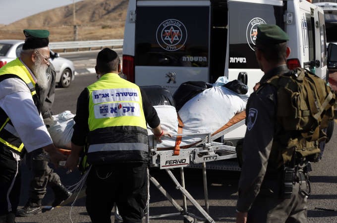 عناصر منالشرطة والاسعاف الاسرائيلي يدفعون عربة عليها جثمان الشهيد الفلسطيني الذي قضى في الخليل امس افپ

