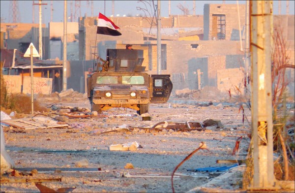 الية تابعة للقوات العراقية في احد احياء الرمادي المحررة وفي الاطار جثمان قائد جيش الاسلام زهران علوش افپ