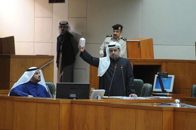 راكان النصف يرفع علبة دواء مستوردة من الخارج ليقارنها بالاسعار المحلية وبجانبه حمدان العازمي