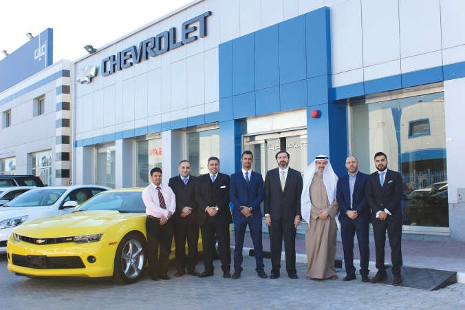 عبدالله مؤذن المدير التنفيذي للمبيعات متوسطا فريق عمل شفروليه الغانم امام صالة العرض الجديدة