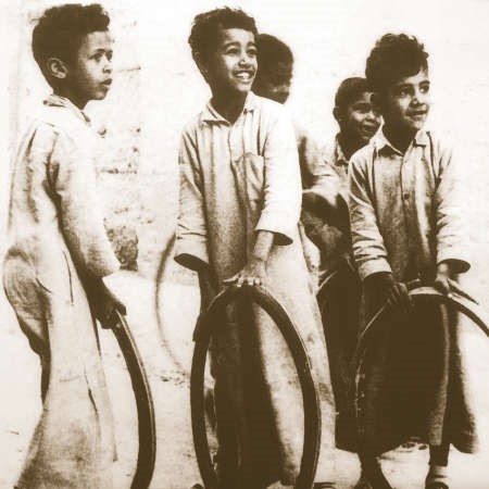 ﻿مجموعة من الصبية يلعبون بالعجلات في احدى البرايح قديما﻿