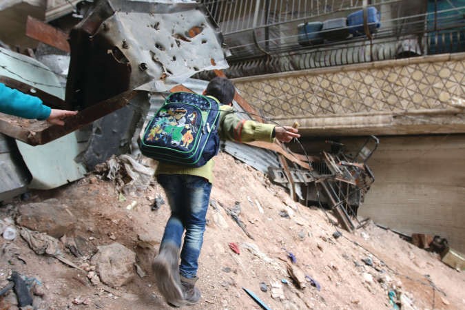 طفل سوري يحاول عبور حاجز رملي لتجنب القناصة في طريقه الى المدرسة في حلب اپ