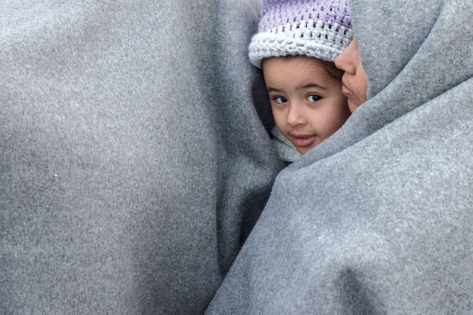 طفل سوري ووالدته يحتميان من البرد ضمن 5 الاف لاجئ عالقين على الحدود اليونانية - المقدونية	اپ ﻿