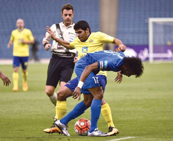 لاعب الهلال ياسر الشهراني يحاول التخلص من رقابة لاعب النصر يحيى الشهري ﻿