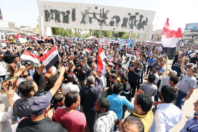 محتجون عراقيون يرفعون العلم الوطني ويرددون هتافات مطالبة بالاصلاح خلال تظاهرة ببغداد امسافپ ﻿