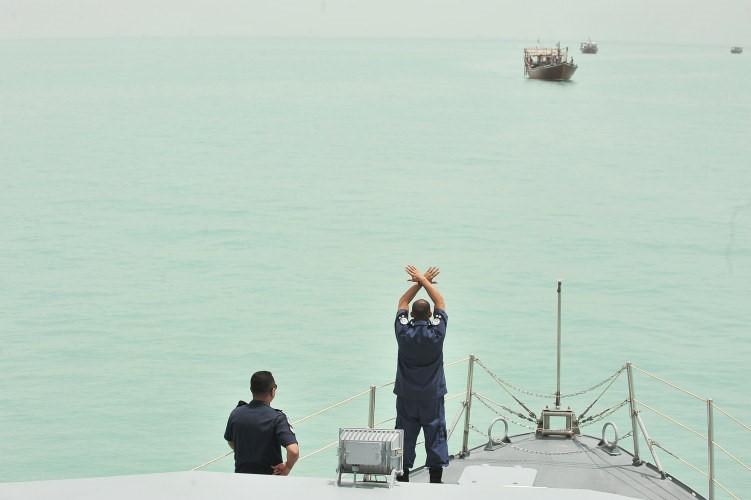احد رجال الخفر يطلب من احدى السفن الايرانية الاقتراب للتفتيش﻿