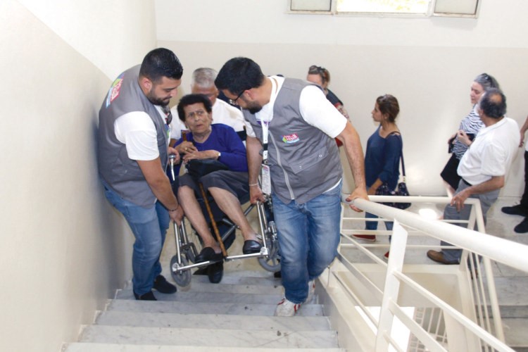 مندوبان يساعدان احدى السيدات على الوصول الى صندوق الاقتراع في جونيه
