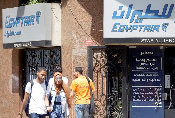 مصريون يمرون امام مكتب لـ مصر للطيران في وسط القاهرة امس الاول	رويترز﻿