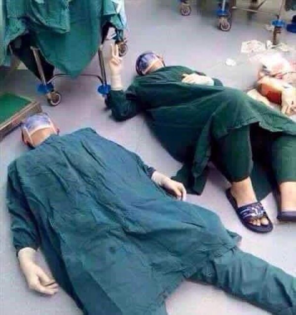 بالصورة: طبيبان يستلقيان على الأرض بعد إجرائهما عملية دامت 32 ساعة.. أحدهما يرفع علامة النصر