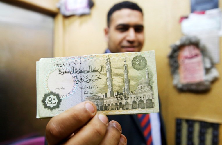 ﻿موظف في احد البنوك المصرية يشير بفئة الخمسين قرشا بعد اعادة طباعتها مجددا 	رويترز﻿