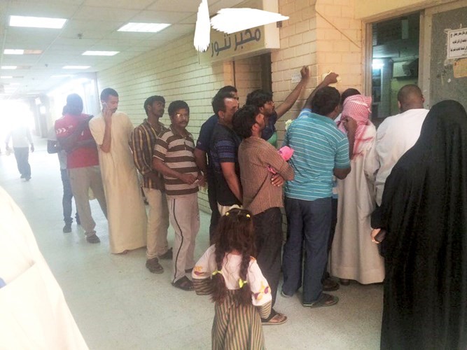امراة تنتظر دورها للحصول على بعض الخبز امام طابور من الرجال﻿