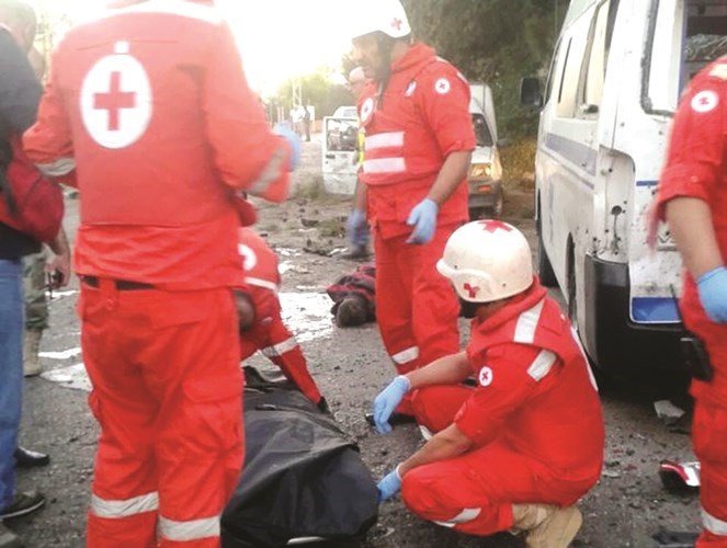 مسعفون من الصليب الاحمر اللبناني ينقلون جثث ضحايا العمليات الانتحارية في القاعمحمود الطويل 
