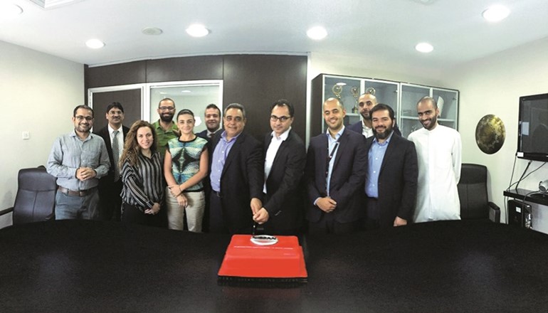 نبيل توما ومكرم خاطر يتوسطان فريقي عمل البابطين وميماك اوجلفي لحظة تقطيع كيكة الاحتفال بالتعاون الجديد