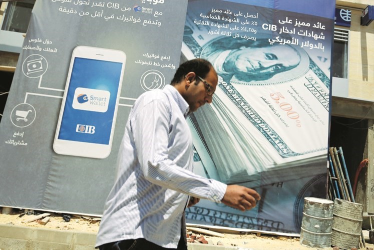 مواطن مصري يمر بجوار صورة كبيرة للدولار على مبنى جديد لاحد البنوك الاجنبية في القاهرة امسرويترز﻿