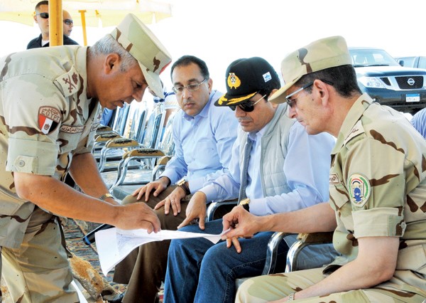 السيسي مرتديا كابيحمل شعار قناة السويس الجديدةخلال جولته في مشروع مدينة الجلالة