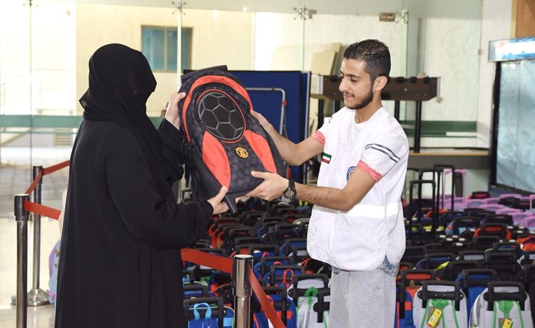 احدى السيدات تتسلم حقيبة المدرسة لابنها	ريليش كومار﻿