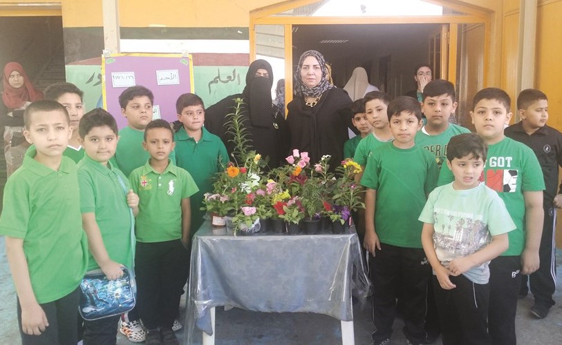 فاطمة العنزي ومنال عبد الهادي وايمان سالم يتوسطون طلبة شاركوا في المسابقة 