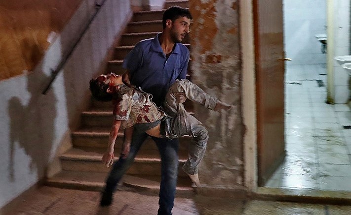 سوري يحمل صبيا مصابا بجروح خطيرة في محاولة لاسعافه باحد المستشفيات في دوما امس	 (ا ف پ)﻿