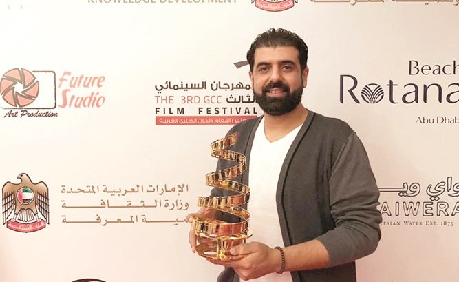 المخرج السينمائي احمد الخلف حاملا درع تكريمه في مهرجان السينما الخليجية﻿