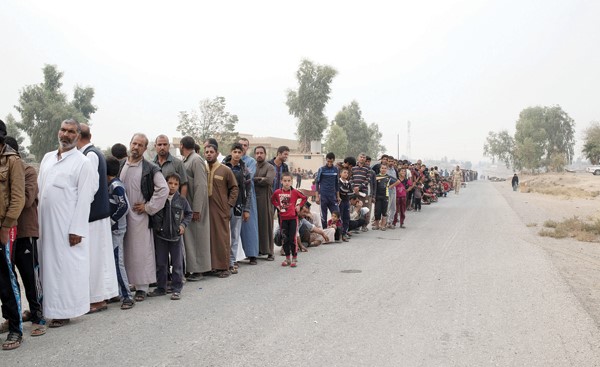  طابور من النازحين العراقيين الفارين بسبب معركة الموصل يتلقون المساعدات الإنسانية من «اليونيسيف» (رويترز)