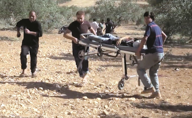 صورة ماخوذة من فيديو تظهر محاولة رجال الانقاذ اسعاف احد الضحايا نتيجة الغارات على مدرسة في حاس امس 	افپ﻿