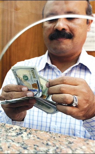 «المركزي المصري» يعوم سعر الجنيه للقضاء على السوق السوداء وتحقيق متطلبات قرض صندوق النقد الدولي.. وفي الصورة أحد المتعاملين في محلات الصرافة في مدينة القاهرة 		(رويترز)