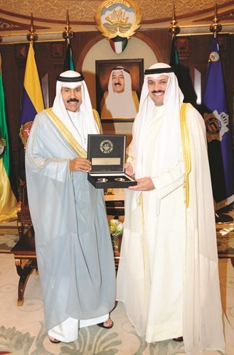 سمو ولي العهد الشيخ نواف الأحمد يتلقى المسكوكة التذكارية لعملة بيزه من د. محمد الهاشل﻿