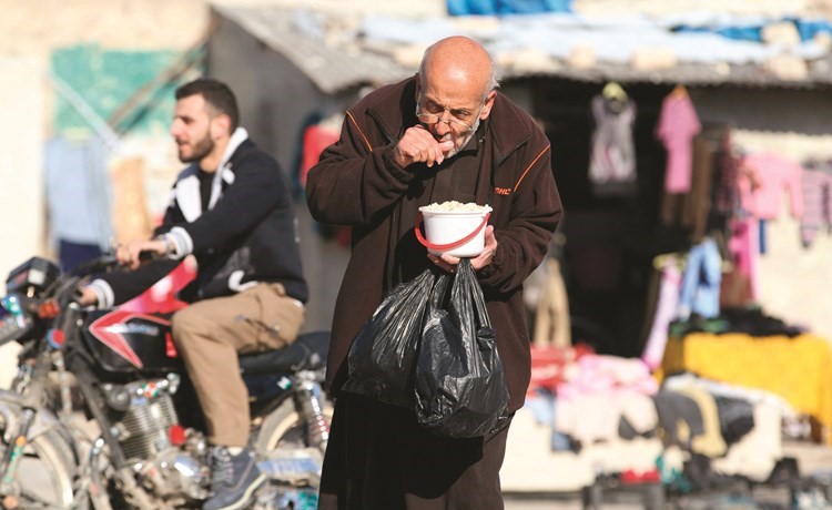 سوري يتناول طعاما تم توزيعه كمساعدات في إحدى المناطق التي يسيطر عليها المعارضون في حلب 	(رويترز)﻿