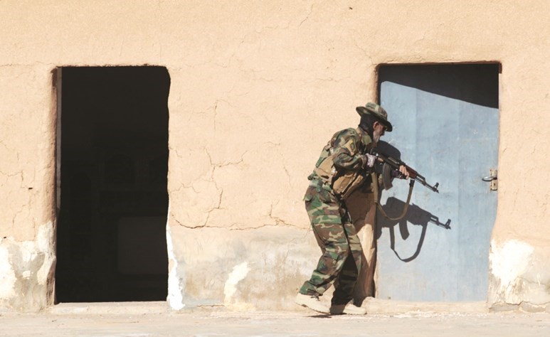 احد عناصر الحشد الشعبي يهم باقتحام احد منازل المدنيين في حي التفاح بتلعفر امس	(رويترز) ﻿