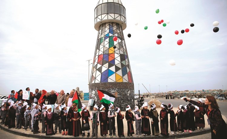 أطفال فلسطينيون يطيرون البالونات خلال تجمع في ميناء غزة للاحتفال باليوم العالمي للتضامن مع الشعب الفلسطيني أمس (أ.ف.پ)