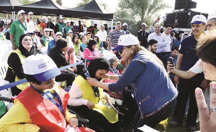 نائب الرئيس التنفيذي لمجموعة البنك الوطني شيخة البحر تكرم إحدى المشاركات الفائزات ﻿﻿من ذوي الاحتياجات الخاصة بميدالية الفوز ﻿