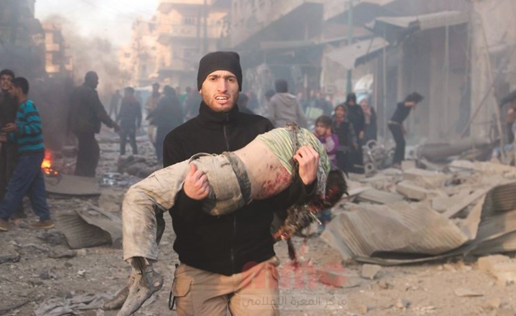 صورة نشرها مركز المعرة الاعلامي لسوري يحمل جثة طفل قتل في الغارات على معرة النعمان بريف ادلب	(انترنت)﻿
