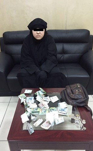 المتسولة وأمامها الأموال التي جمعتها﻿