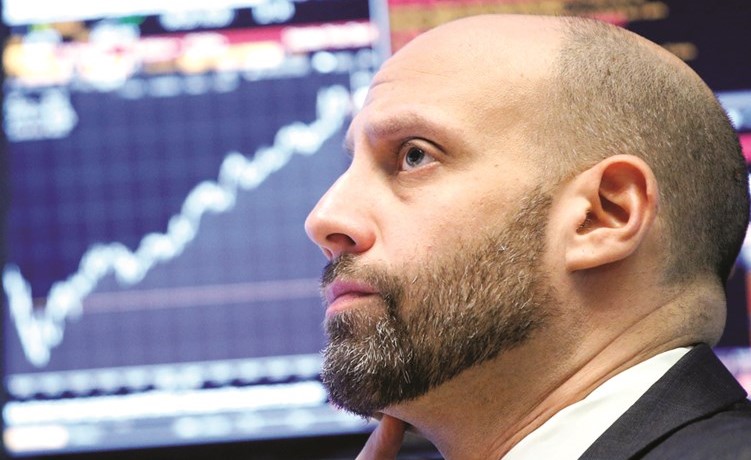 متداول يراقب التداولات في بورصة نيويورك.. والأسواق تترقب قرار رفع الفائدة	(رويترز)
