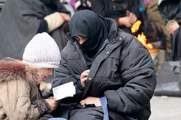 سيدة تقرأ مع طفلها القرآن بانتظار اجلائهما من شرق حلب       	(رويترز)